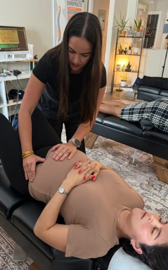 Chiropractor applies treatment to patient lying on a therapy table in a clinic, focusing on the torso area.