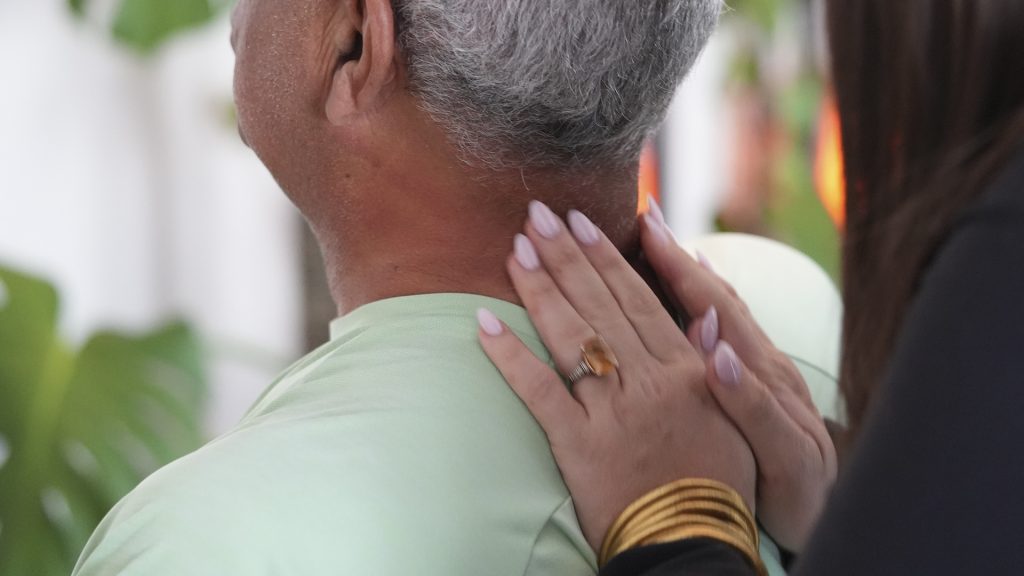 How Stress Can Show Up as Neck Shoulder and Back Pain - Express Life Chiropractic | Chiropractor Fort Lauderdale. Person with gray hair wearing a light green shirt is being touched on the back/neck by someone with pink manicured nails and a ring, offering a comforting touch.
