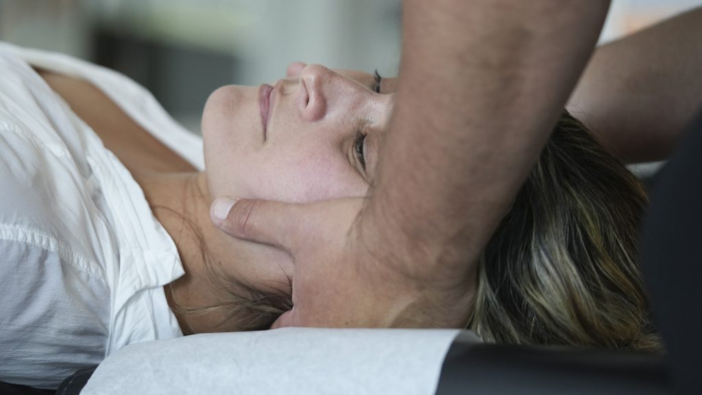 Waking Up With Neck Pain Your Sleeping Position May Be the Problem - Express Life Chiropractic | Chiropractor Fort Lauderdale. Person lying on their side while a therapist supports their neck during a massage.